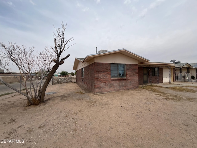 9885 Lilly Dr, El Paso, TX 79927 - view of property exterior with fence, brick siding, and an attached garage