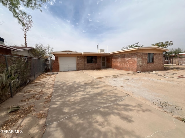 9874 Staubach Dr, El Paso, TX 79927 - rear view of house featuring brick siding, driveway, fence, and a garage