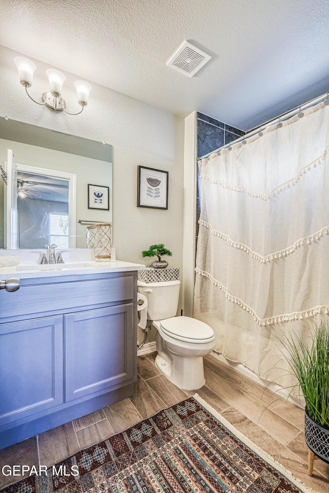 full bathroom with toilet, vanity, wood finish floors, a shower with curtain, and a textured ceiling