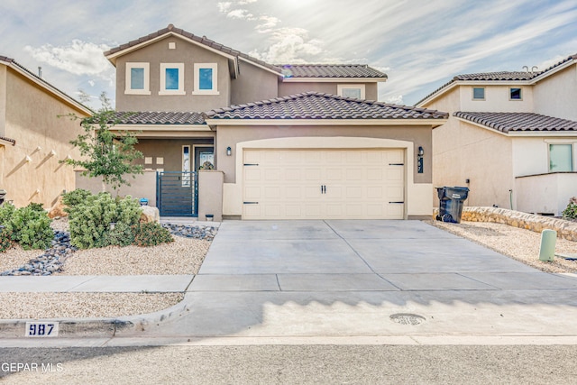 mediterranean / spanish home featuring concrete driveway, a garage, a tiled roof, and stucco siding