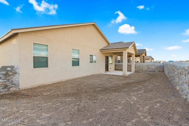 rear view of house featuring stucco siding, a patio, and fence
