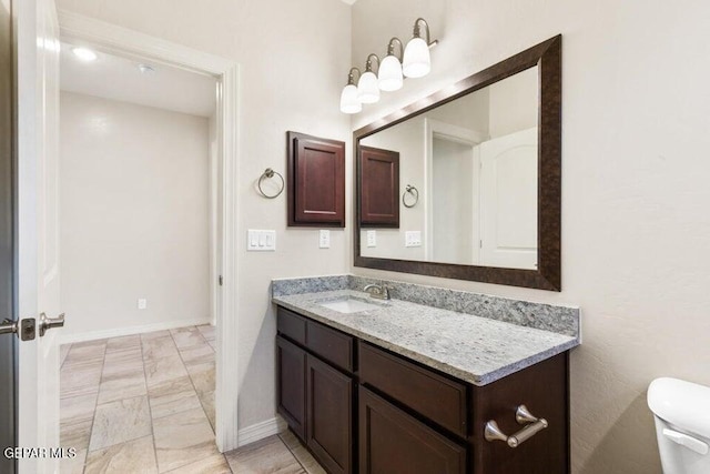 bathroom featuring marble look tiles, baseboards, vanity, and toilet