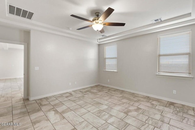 spare room featuring a tray ceiling, a ceiling fan, and baseboards