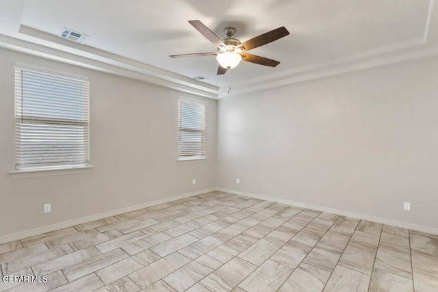 unfurnished room featuring a raised ceiling, ceiling fan, and baseboards