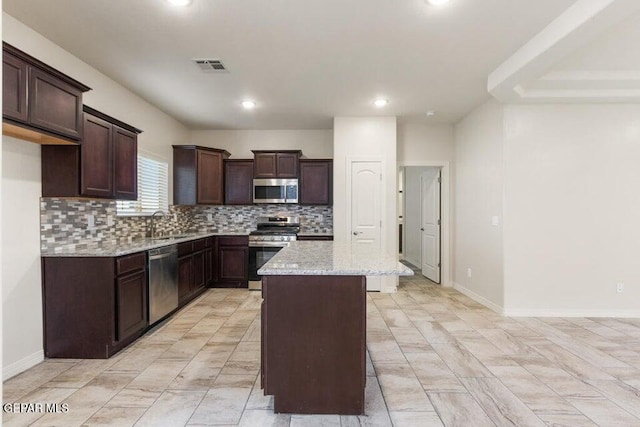 kitchen with appliances with stainless steel finishes, tasteful backsplash, dark brown cabinetry, a center island, and recessed lighting