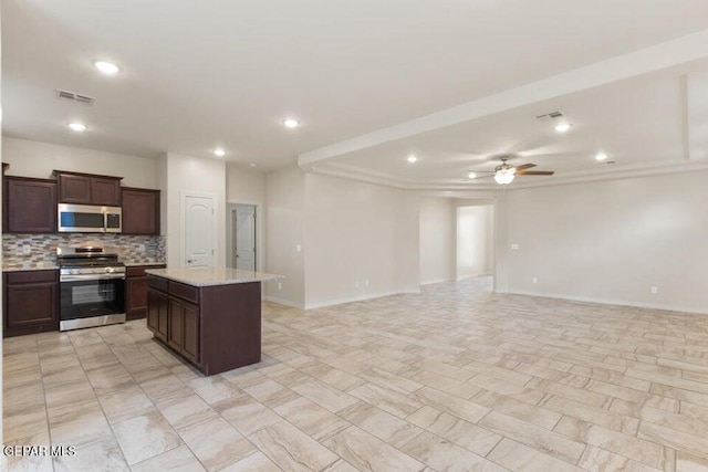 kitchen featuring appliances with stainless steel finishes, decorative backsplash, ceiling fan, open floor plan, and a kitchen island