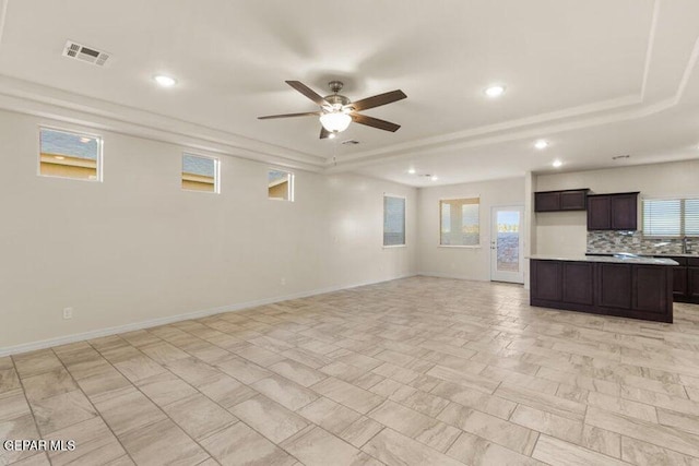 unfurnished living room with ceiling fan, recessed lighting, baseboards, and a raised ceiling
