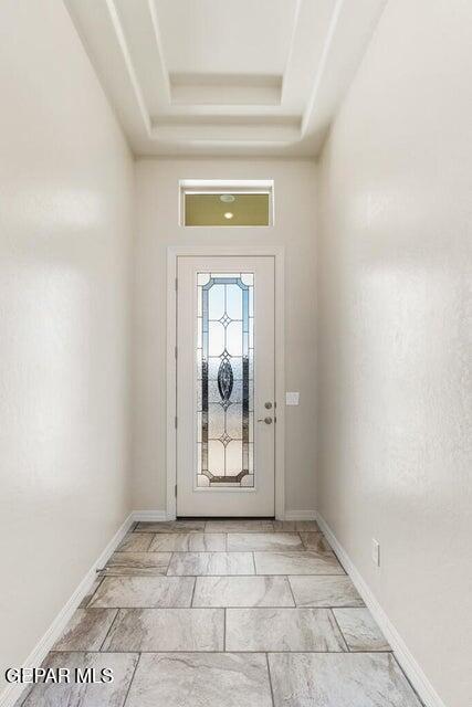 entrance foyer featuring a tray ceiling and baseboards
