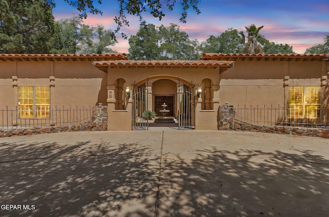 view of front of home with stucco siding, fence, and a tile roof