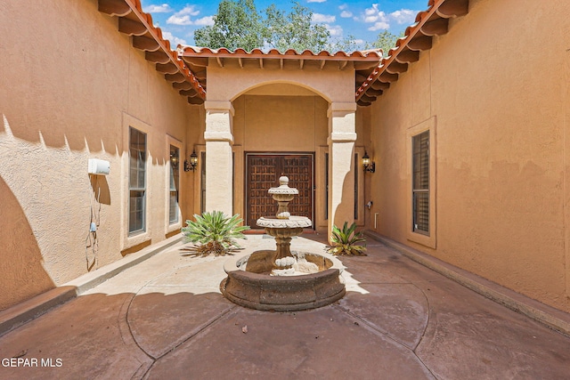 doorway to property featuring stucco siding, a tile roof, and a patio