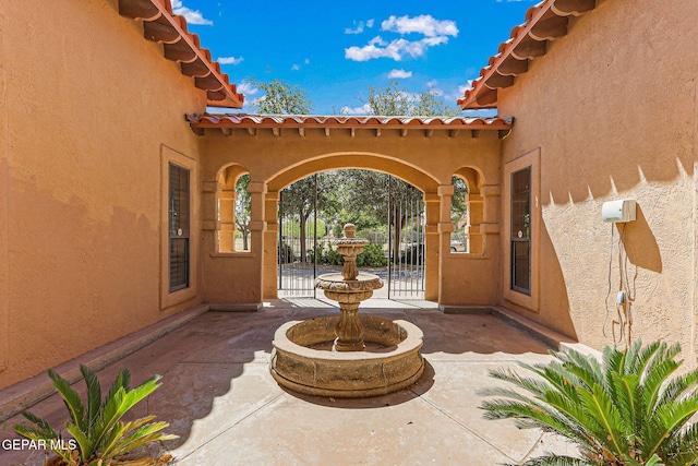 view of exterior entry featuring stucco siding, a patio, and a tiled roof