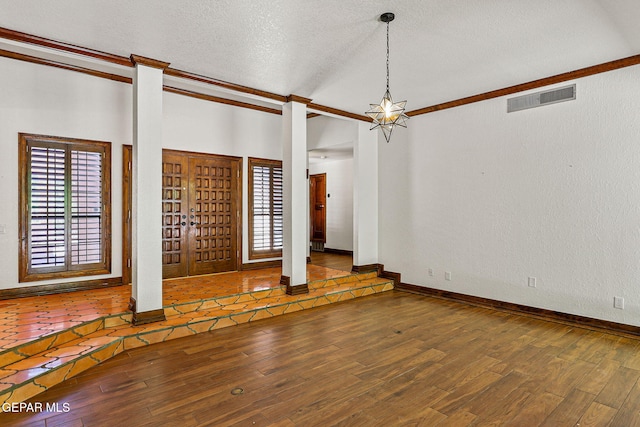 spare room with wood finished floors, plenty of natural light, a textured ceiling, a chandelier, and baseboards