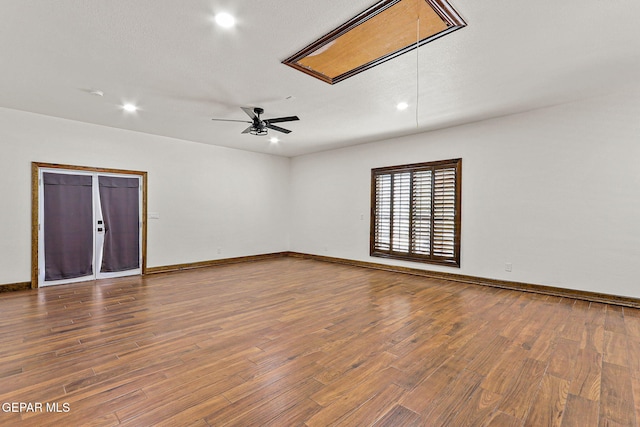unfurnished room with attic access, wood finished floors, recessed lighting, and baseboards