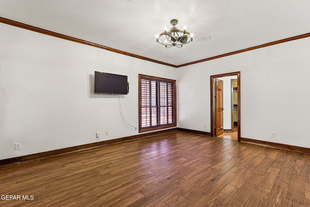 spare room featuring a chandelier, ornamental molding, dark wood-style floors, baseboards, and a textured ceiling