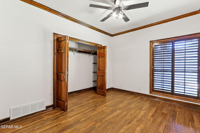 unfurnished bedroom featuring ornamental molding, dark wood-style flooring, a closet, baseboards, and ceiling fan