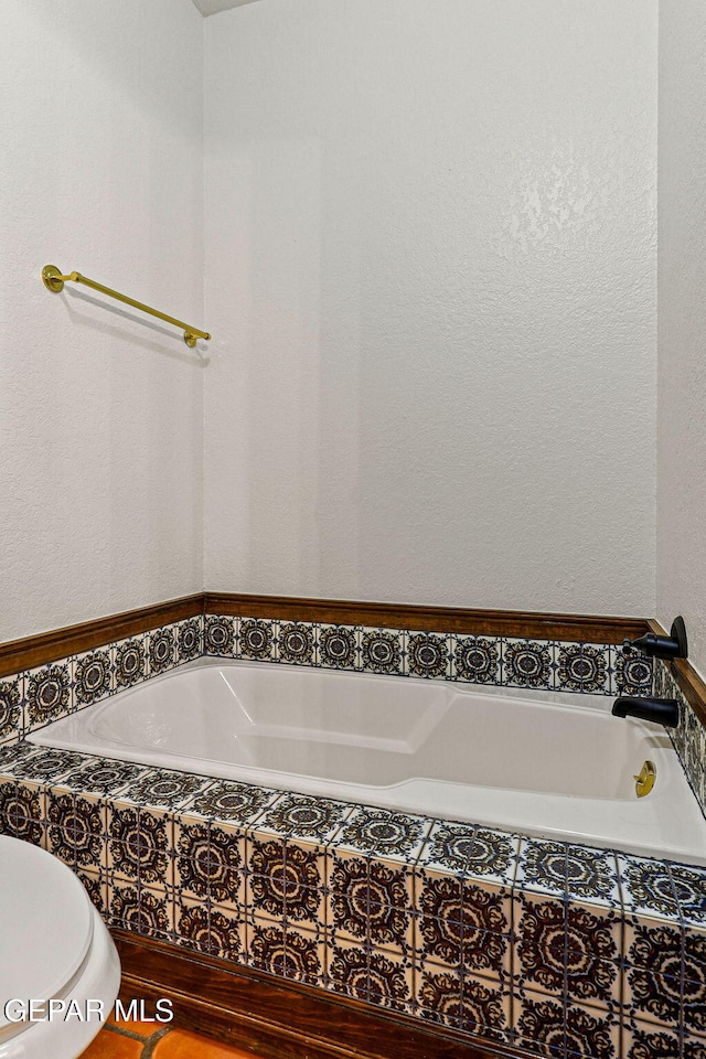 full bathroom featuring a bath and a textured wall