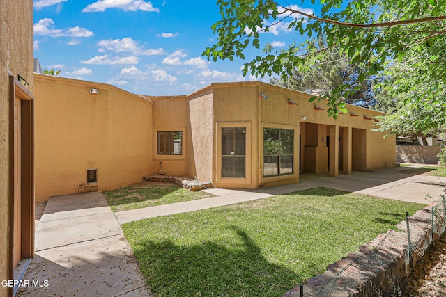 view of front of property with stucco siding, a front lawn, and a patio area