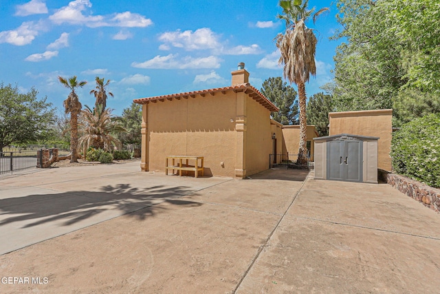 view of side of property featuring a chimney, fence, stucco siding, and a patio area