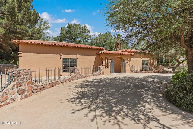 mediterranean / spanish-style home featuring a tile roof, stucco siding, and a fenced front yard