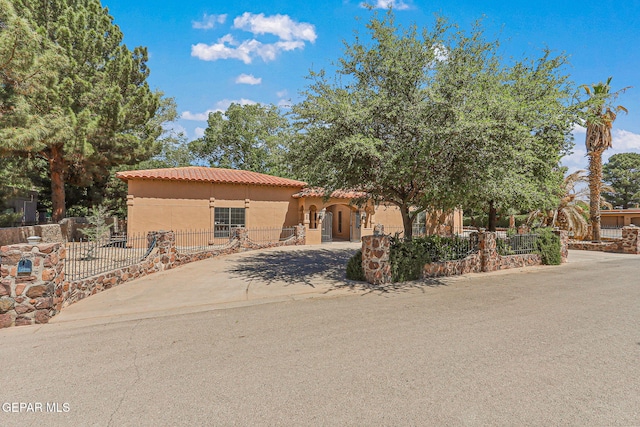 mediterranean / spanish-style home featuring stucco siding, a tile roof, fence, and concrete driveway