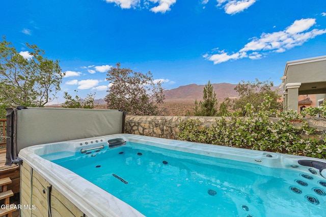 view of pool with a hot tub and a mountain view