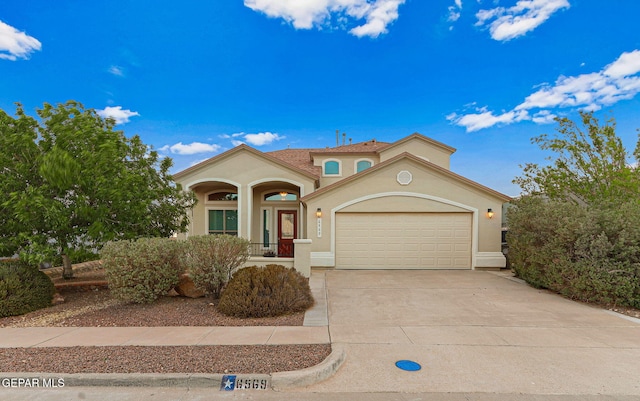 mediterranean / spanish home with stucco siding, an attached garage, driveway, and covered porch
