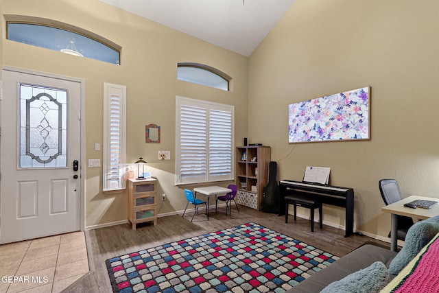 foyer entrance with wood finished floors, high vaulted ceiling, healthy amount of natural light, and baseboards