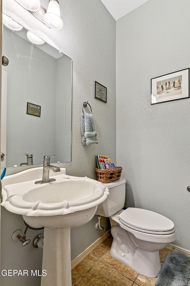 bathroom with toilet, baseboards, and tile patterned floors