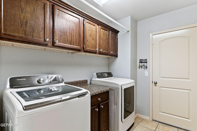 laundry area featuring washing machine and dryer, cabinet space, light tile patterned floors, and baseboards