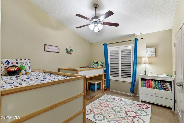 carpeted bedroom with vaulted ceiling, a textured ceiling, a ceiling fan, and baseboards