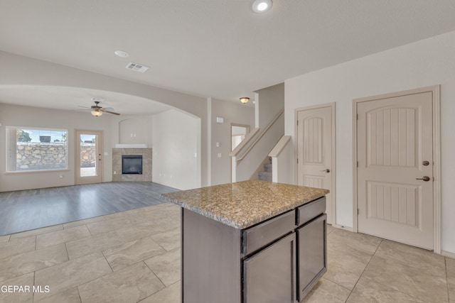 13824 Hollywood Dr, Horizon City, TX 79928 - kitchen with a ceiling fan, a kitchen island, a tile fireplace, and arched walkways
