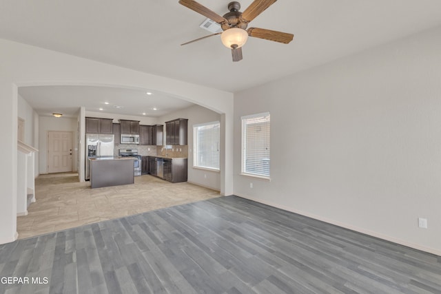 13824 Hollywood Dr, Horizon City, TX 79928 - unfurnished living room with light wood-style floors, arched walkways, a ceiling fan, baseboards, and recessed lighting