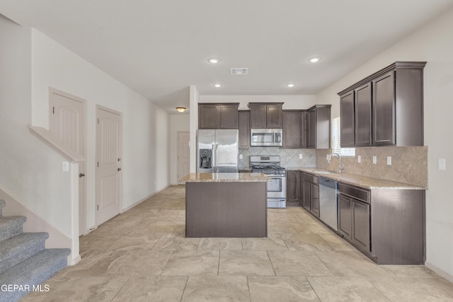 13824 Hollywood Dr, Horizon City, TX 79928 - kitchen with appliances with stainless steel finishes, a sink, dark brown cabinets, backsplash, and a kitchen island