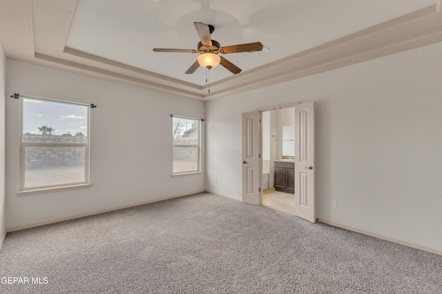 13824 Hollywood Dr, Horizon City, TX 79928 - unfurnished bedroom with a raised ceiling, light colored carpet, connected bathroom, baseboards, and ceiling fan