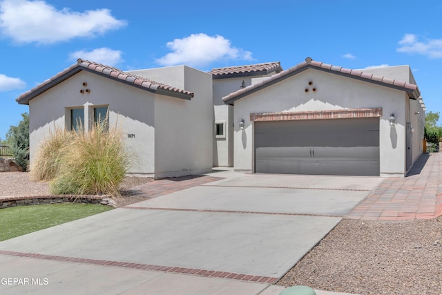 mediterranean / spanish-style house with a garage, driveway, a tiled roof, and stucco siding