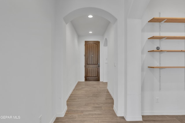 hall featuring arched walkways, wood finished floors, recessed lighting, and baseboards