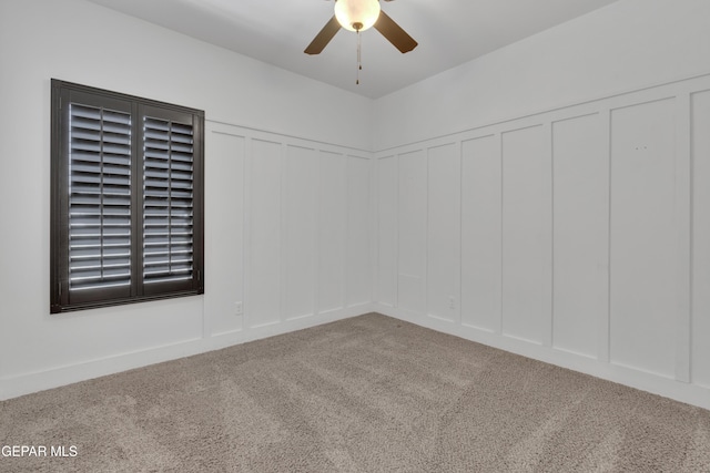 spare room with a decorative wall, ceiling fan, and carpet