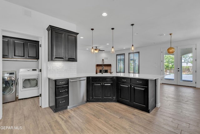 kitchen with a sink, stainless steel dishwasher, separate washer and dryer, a peninsula, and light countertops