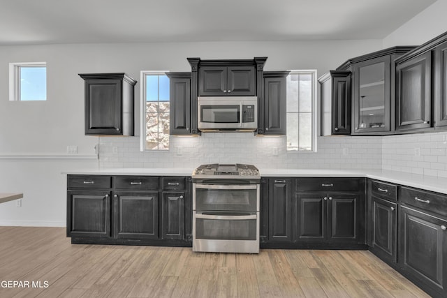 kitchen featuring appliances with stainless steel finishes, dark cabinets, light countertops, and tasteful backsplash