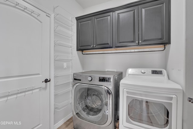washroom featuring washer and dryer, cabinet space, and light wood finished floors