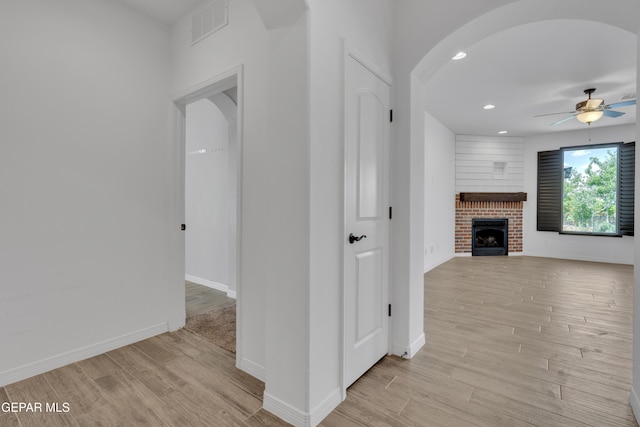 hallway featuring light wood-type flooring, baseboards, arched walkways, and recessed lighting