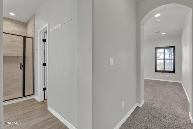 corridor with arched walkways, recessed lighting, and baseboards