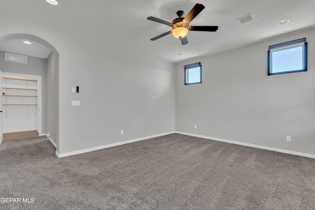 unfurnished room featuring carpet floors, ceiling fan, arched walkways, and healthy amount of natural light