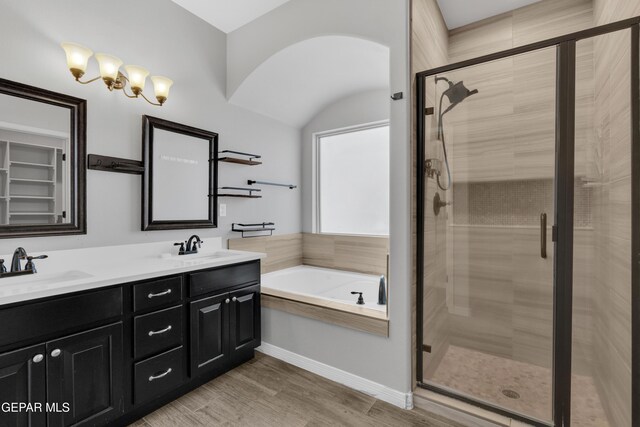bathroom featuring a garden tub, a shower stall, wood finished floors, double vanity, and vaulted ceiling