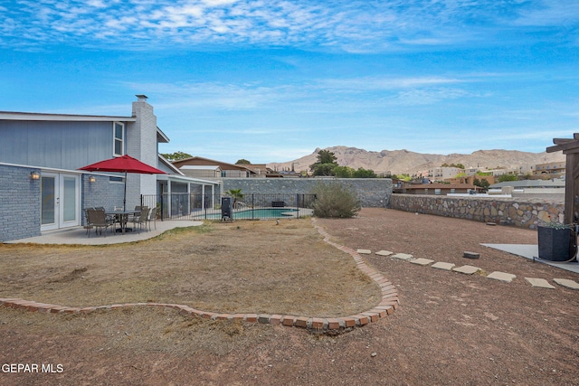 fenced backyard with a mountain view, a patio area, and french doors