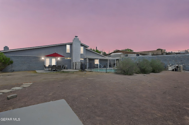 back of property featuring fence, a patio area, and a chimney