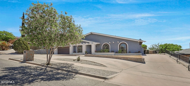 view of front of home with curved driveway, fence, an attached garage, and brick siding