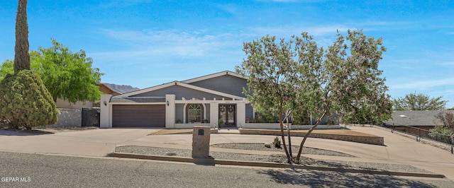 ranch-style home featuring driveway, a garage, and fence