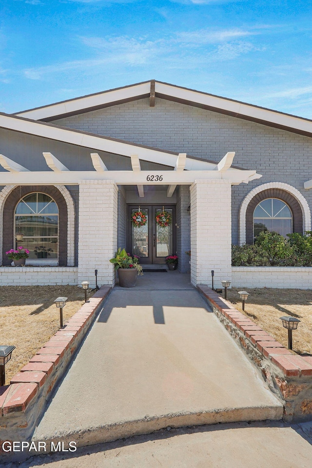 entrance to property featuring french doors and brick siding