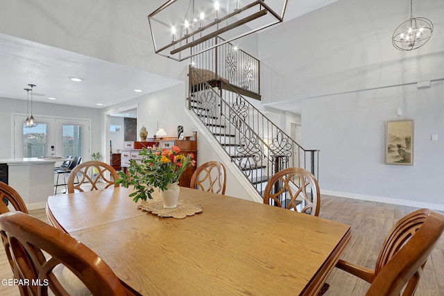 dining room featuring a chandelier, wood finished floors, stairway, a towering ceiling, and baseboards